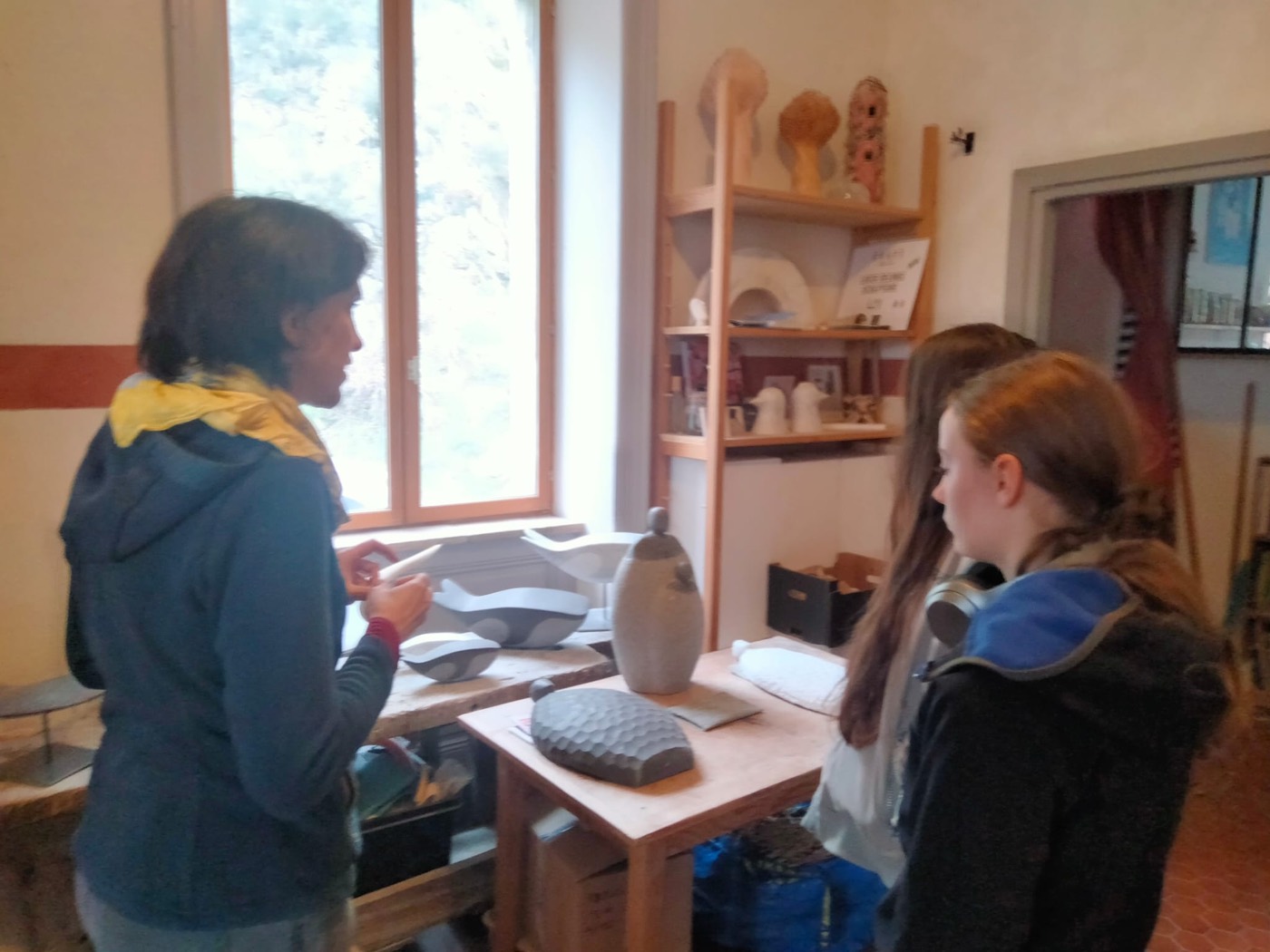 Une artiste explique son travail à deux jeunes dans son atelier