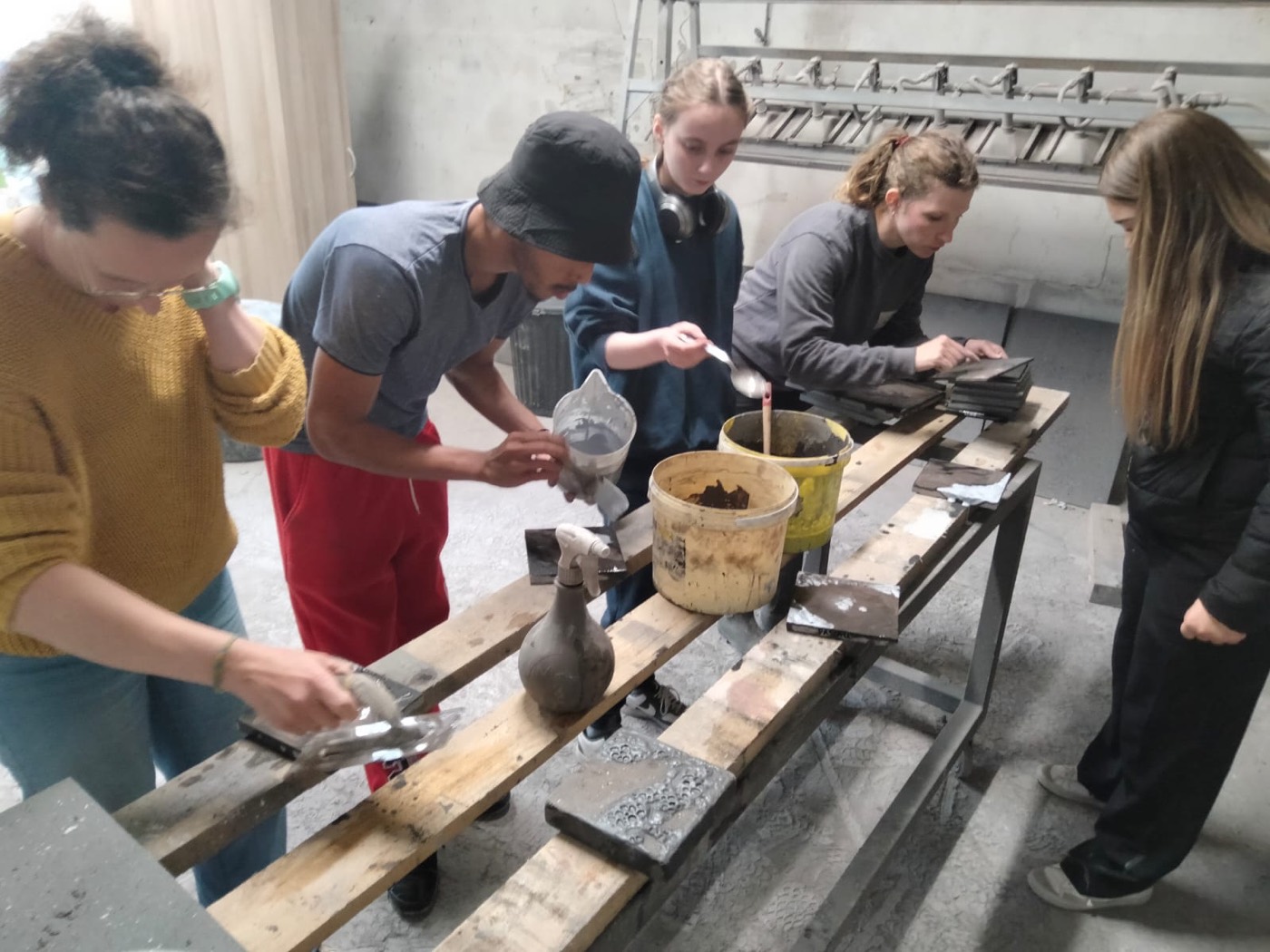 Des jeunes travaillent la matière aux côtés d'un artiste, dans son atelier