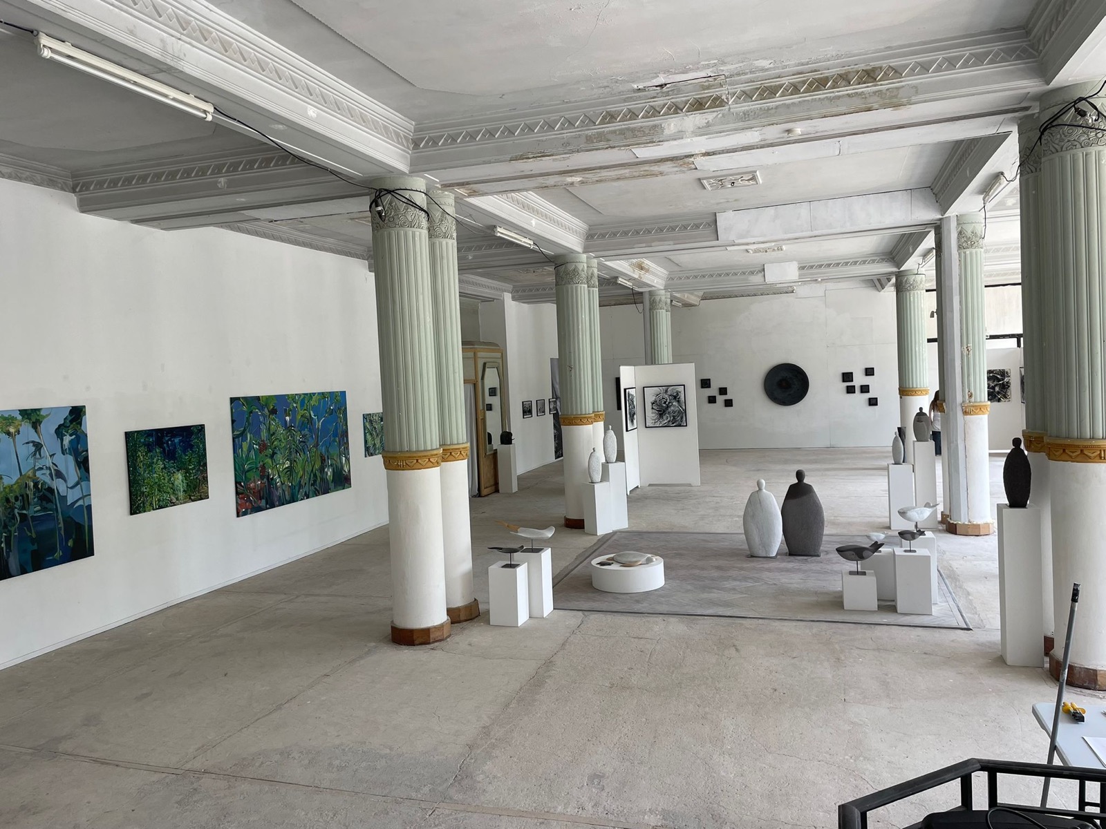 La grande salle à colonnes du Grand Hôtel de Châtel-Guyon transformée en lieu d'exposition : peintures et sculptures